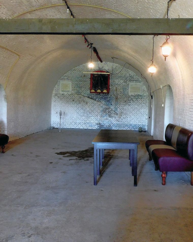 Een gewelfde ruimte in de bomvrije kazerne, ingericht met banken en een tafel