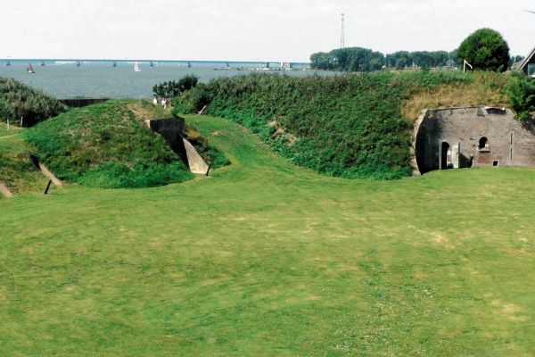 Begroeide wallen en schuilplaatsen op het fortterrein, met de Haringvlietbrug in de verte