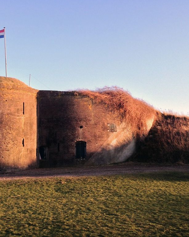 De ronde toren van de bomvrije kazerne met de Nederlandse vlag